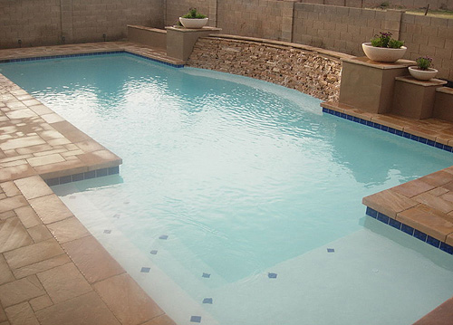 Concrete Swimming pool with shelf and flagstone cascading waterfall